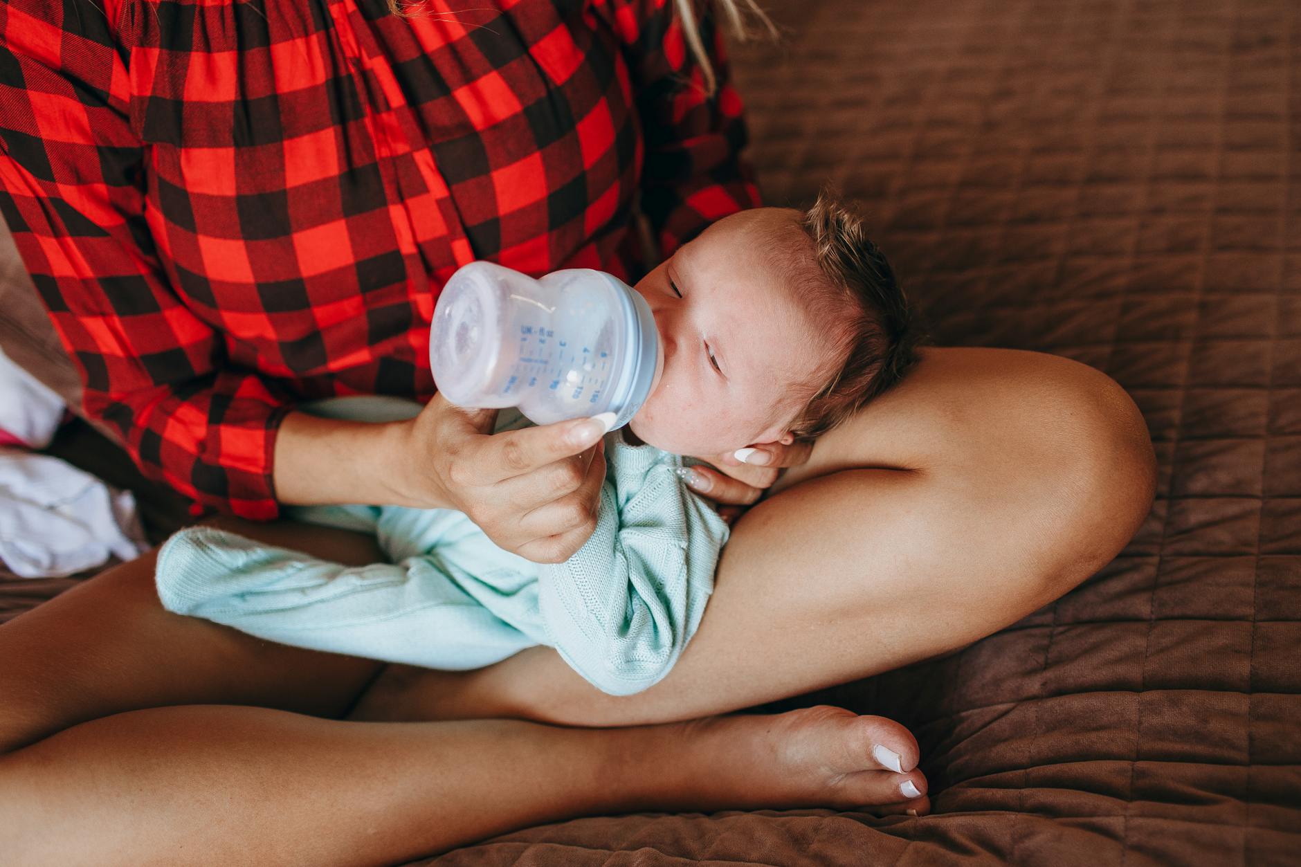 unrecognizable mother bottle feeding infant